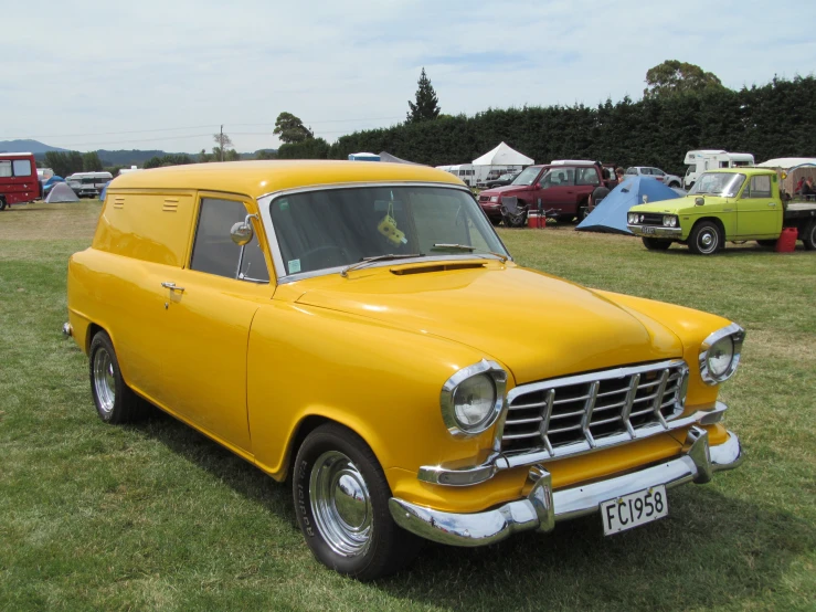 an older yellow station wagon parked in the grass