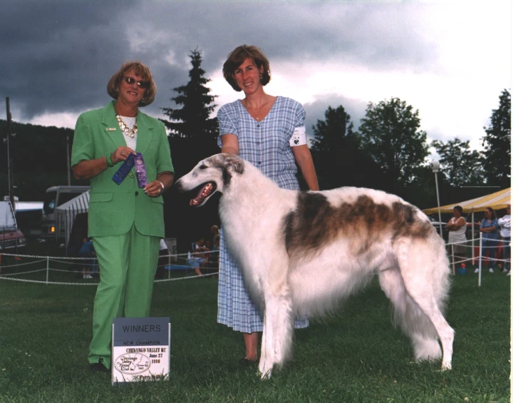 a woman and a man standing next to a dog