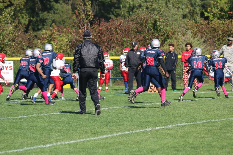 football players are running on the field with their coach