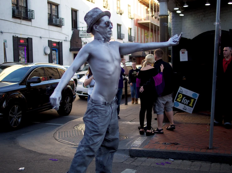 a man in a grey outfit is doing skateboard tricks on the sidewalk