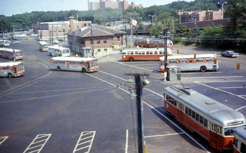 a lot with several different buses and some parking spaces