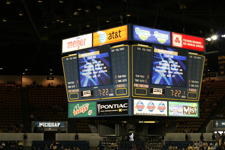 a large screen at an arena shows scoreboards with different teams