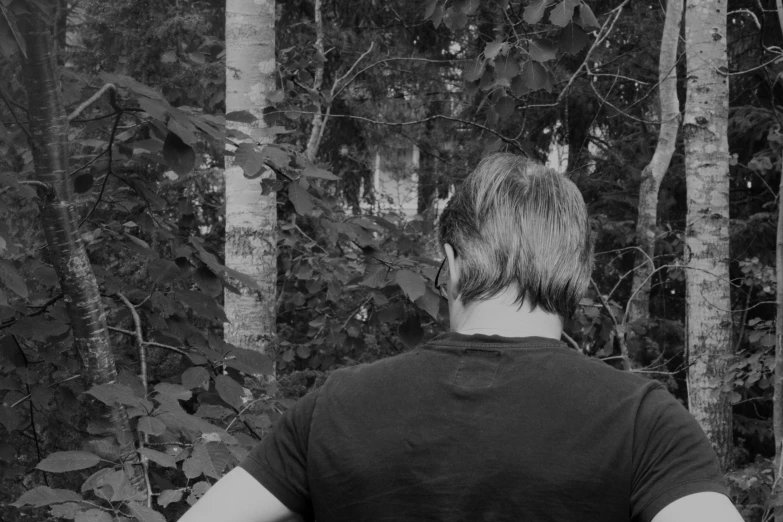 a person in a black shirt stands near many trees