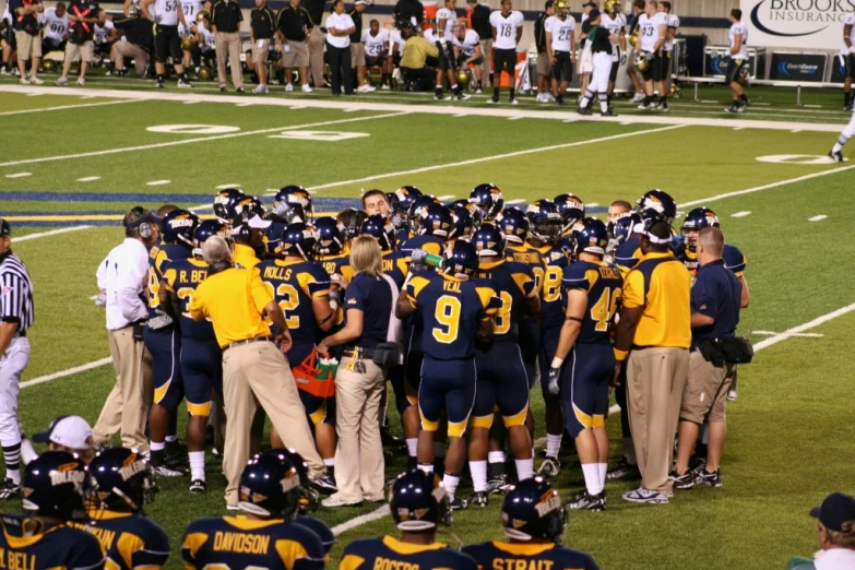 a football team gathered in a huddle on the field