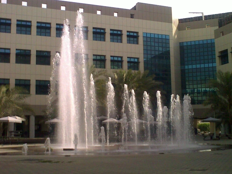 a large building with a building in the background filled with fountains