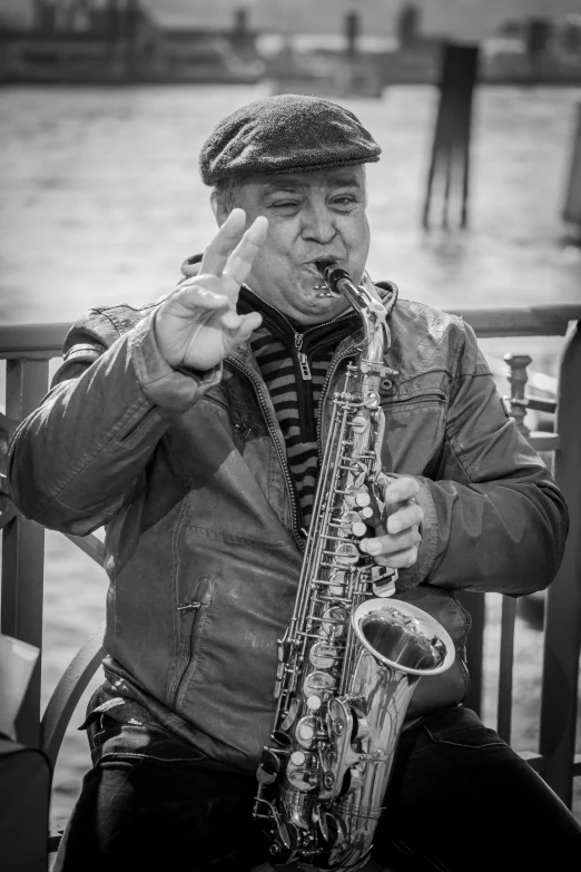a man holding a saxophone while sitting next to water
