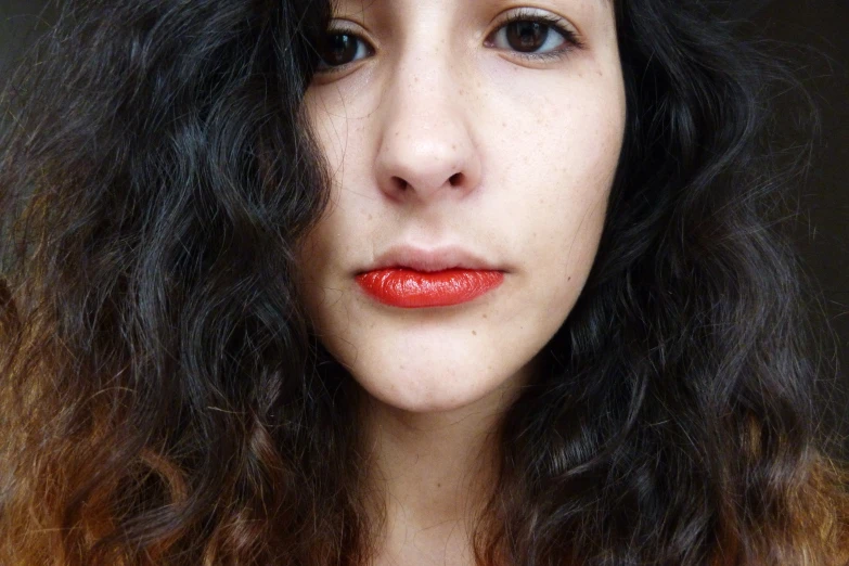 a girl with bright red lipstick looks off into the distance
