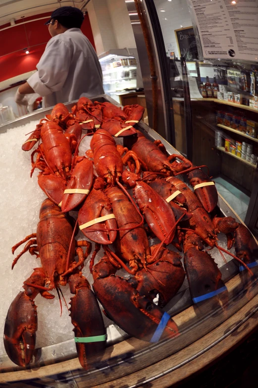 the lobsters are arranged on a counter in front of a man