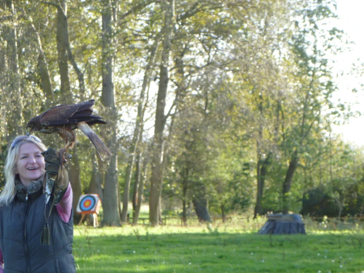 a woman in a park with an eagle and a target