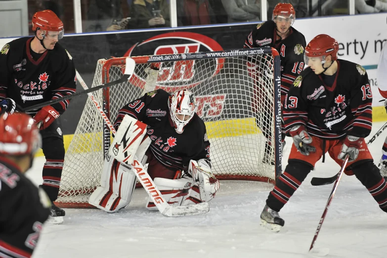 hockey players during a game with the goalie keeping the puck