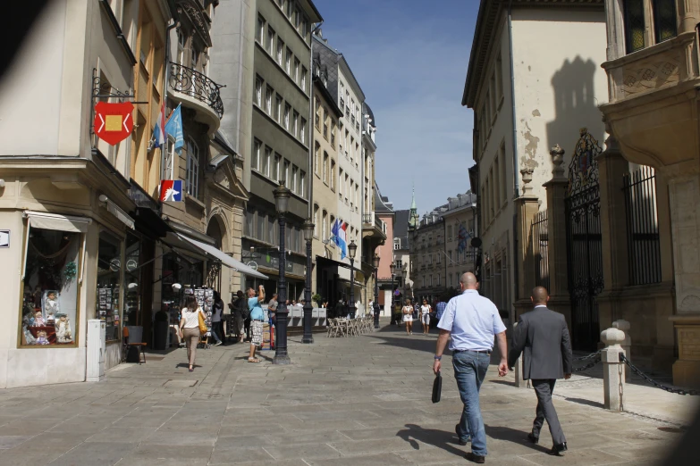 a man in a white shirt walking through a narrow town street