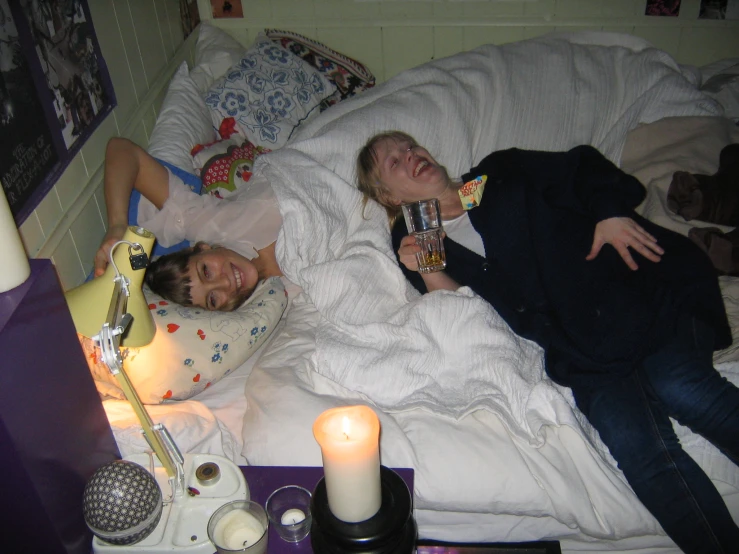 man and woman lying in bed toasting with beverages