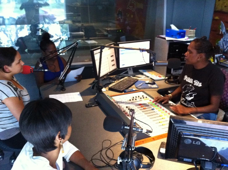 three people sitting at a desk with microphones in front of them