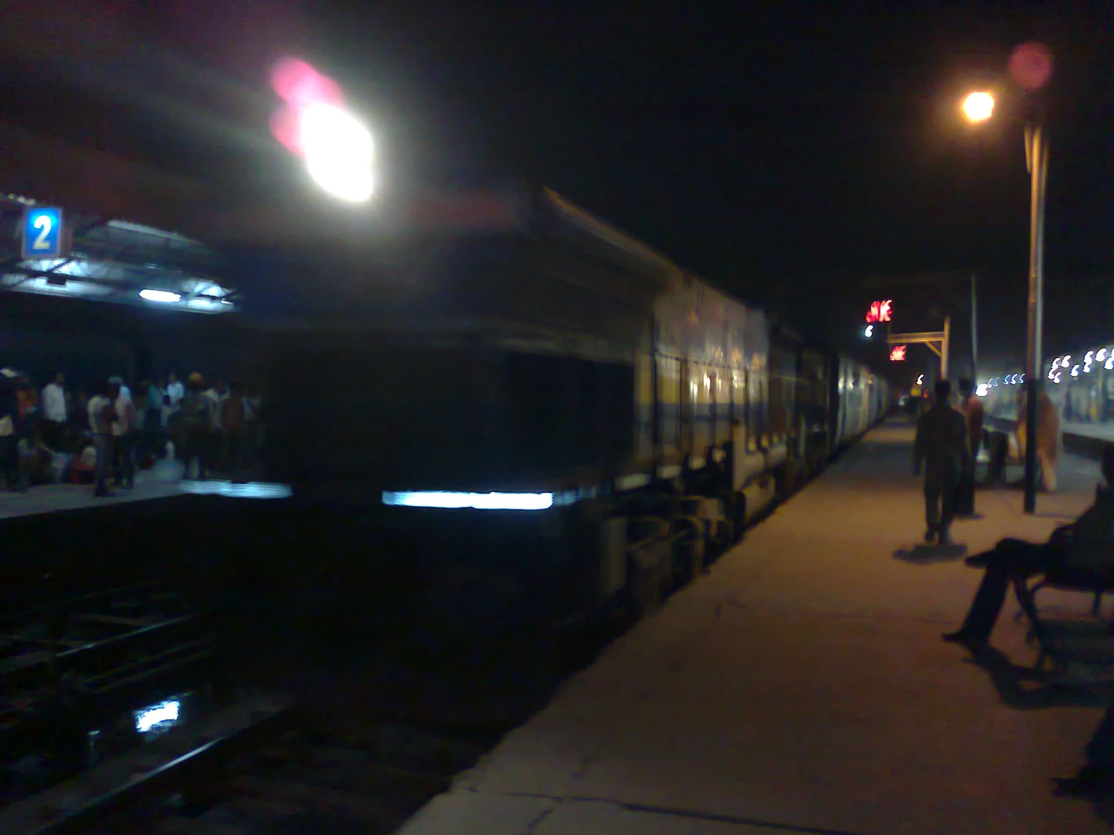 people at a train station waiting for the train to arrive