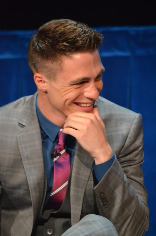 a young man smiles brightly as he sits down