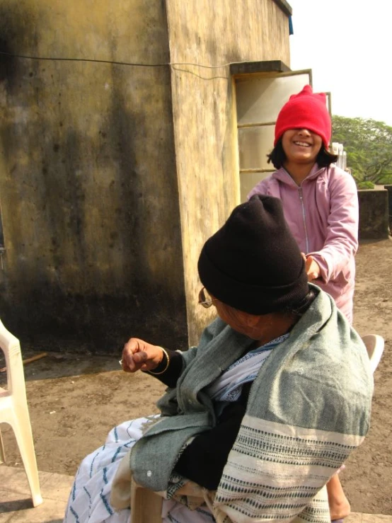 a woman cuts the hair of a man on a chair