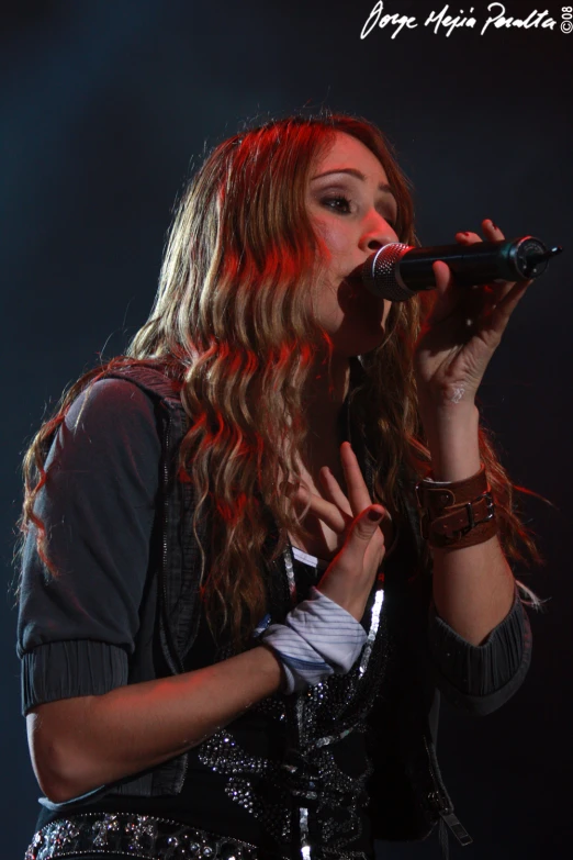 a woman with long curly hair holding a microphone