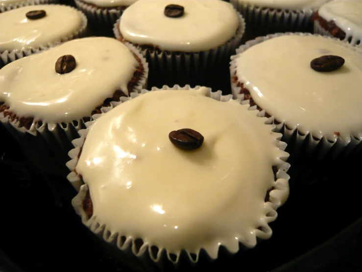 seven cup cakes with white frosting and chocolate sprinkles