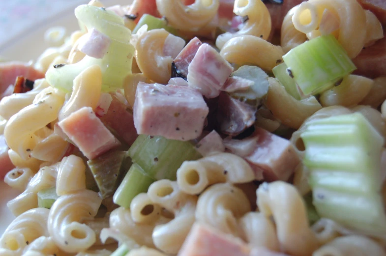 a bowl filled with pasta salad next to a small glass plate