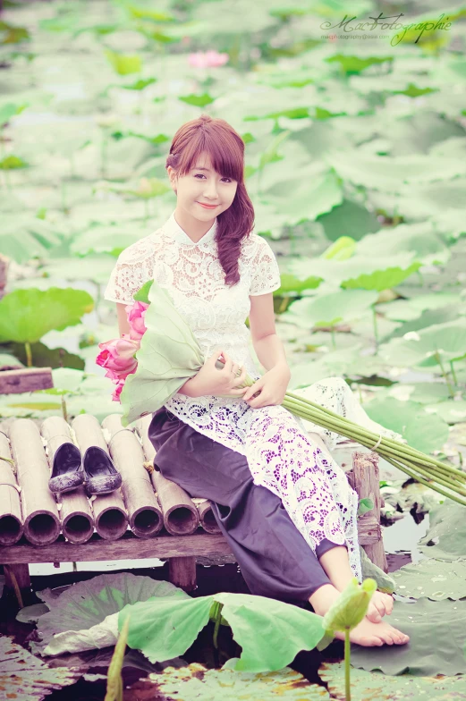 a young asian lady sitting on top of a pond