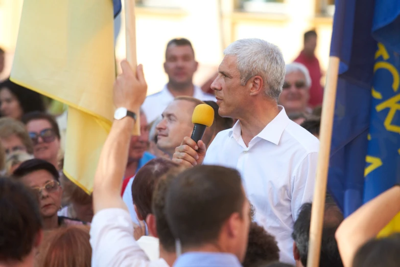 two men on microphones standing in front of a crowd