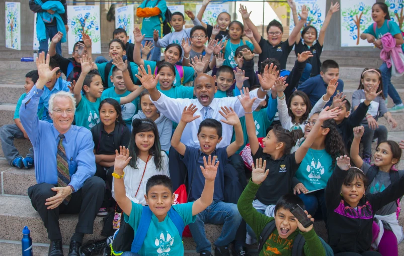 a large group of children with their hands up