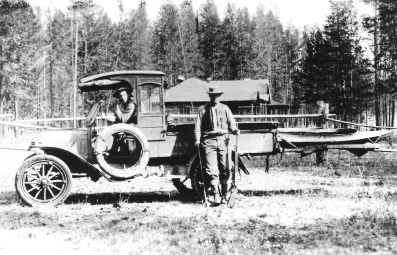 an old car is parked by two men standing in front of it