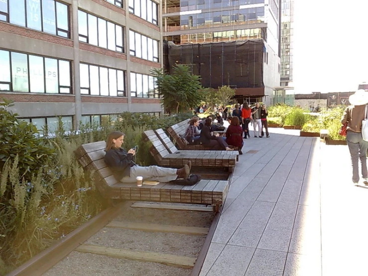 some people are sitting on a large wooden bench