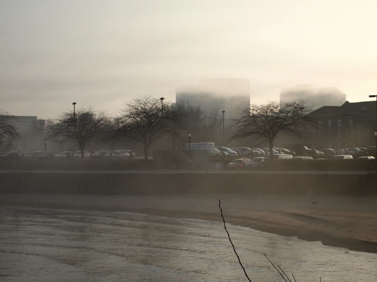 some very tall buildings by the water in the fog