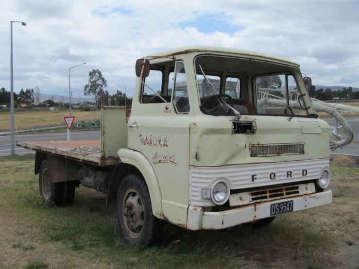 an old tow truck sitting in a grass field