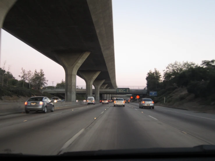 a highway filled with traffic beneath an overpass at dusk