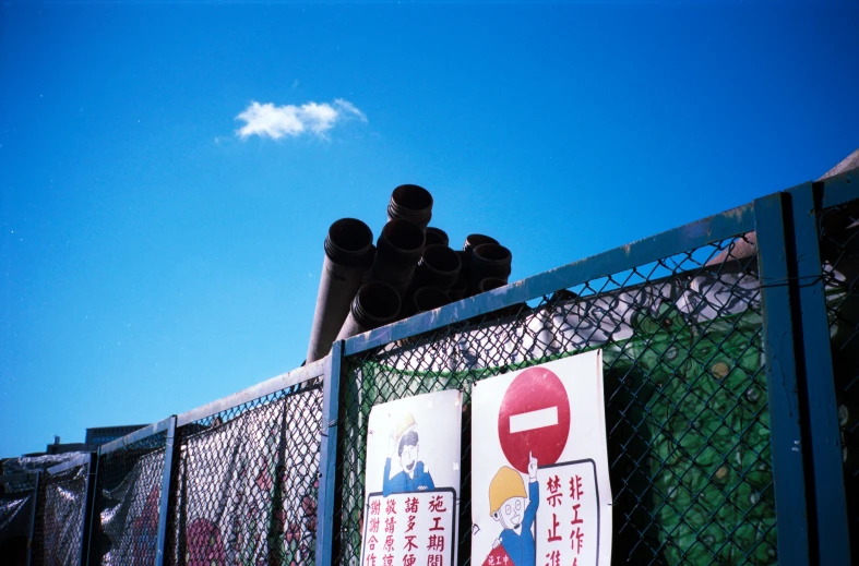 two street signs attached to a fence with metal gate