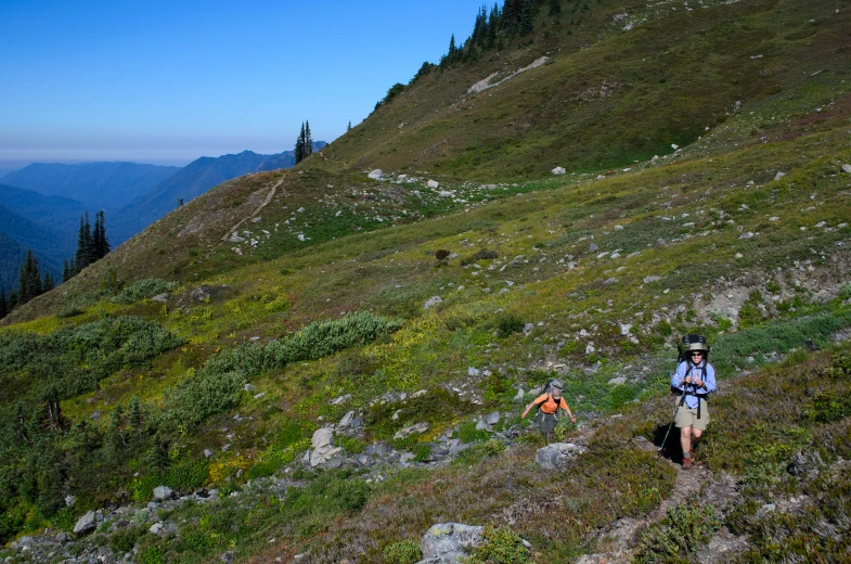 two people trekking on a mountain side