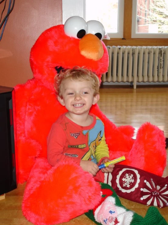 a young child is smiling while wearing a giant elmo mascot