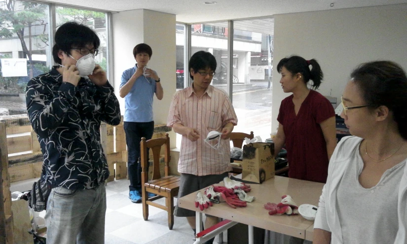 five people drinking coffee while standing in an open room