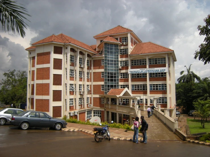 three people standing outside a brown and white building