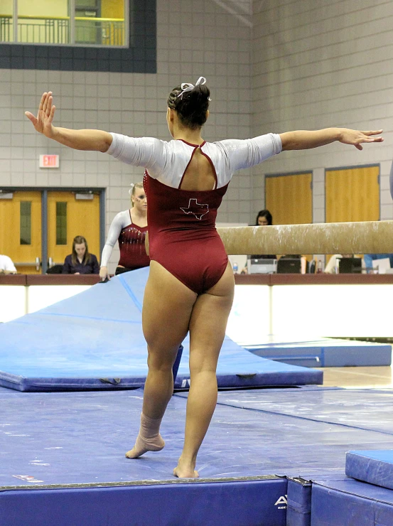 a girl performing on the balance bars while onlookers watch