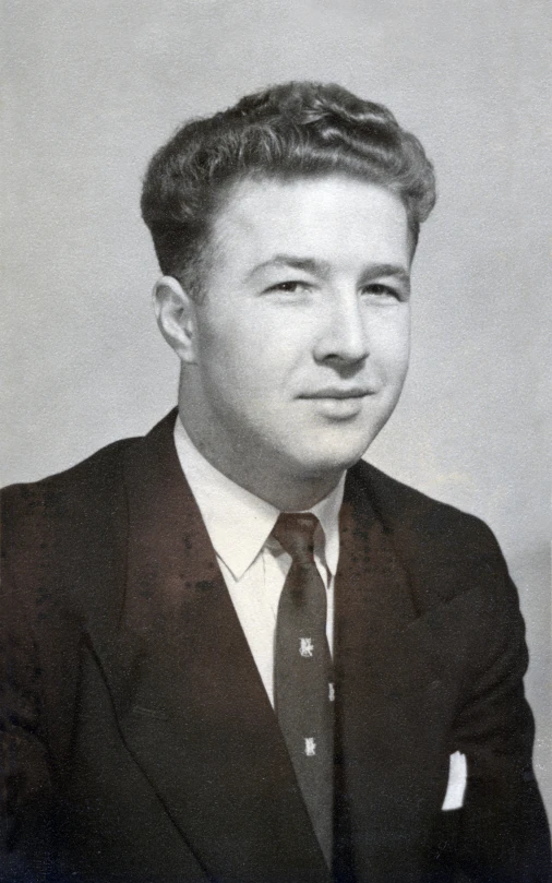 a man with short hair in a black suit and tie