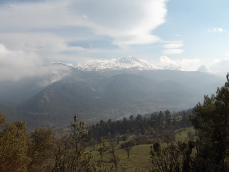 a large mountain range with a small cluster of trees on the far side