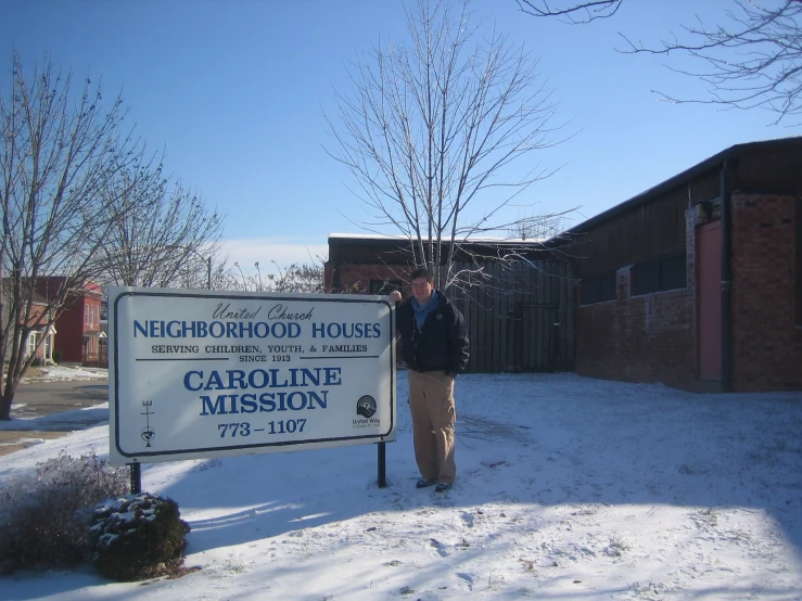 a man in the snow with a sign for a home