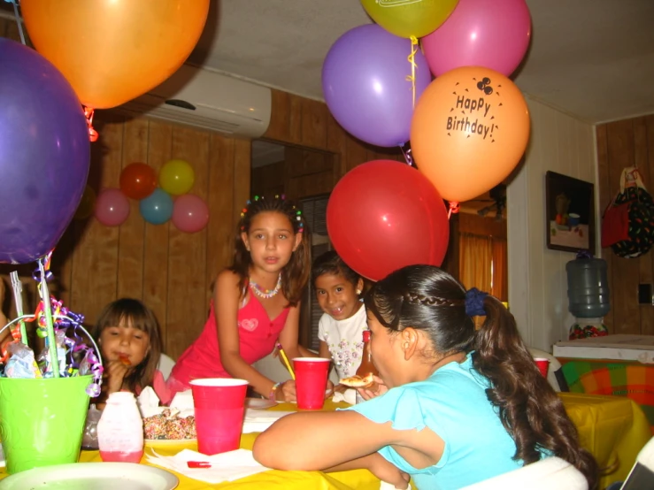 several girls sitting at a birthday party and smiling