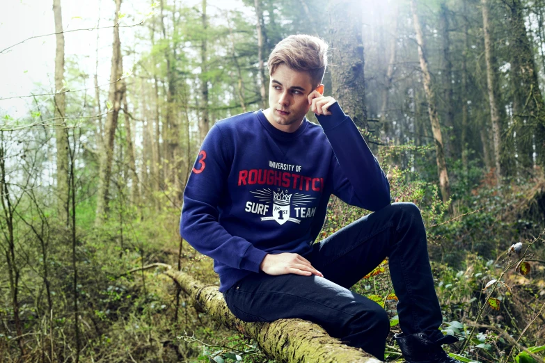 a young man is posing for the camera while sitting in a tree nch