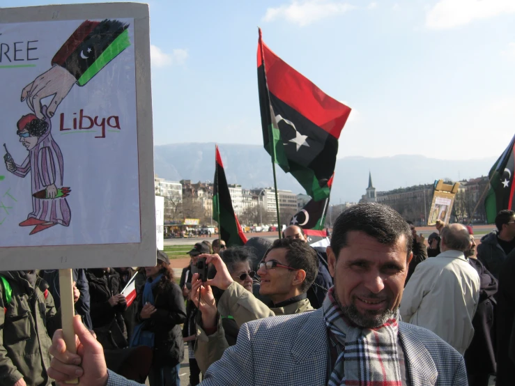 many people are standing outside holding flags and signs