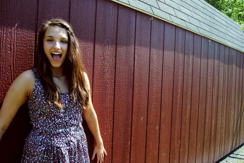 a woman standing near a wooden barn posing for the camera