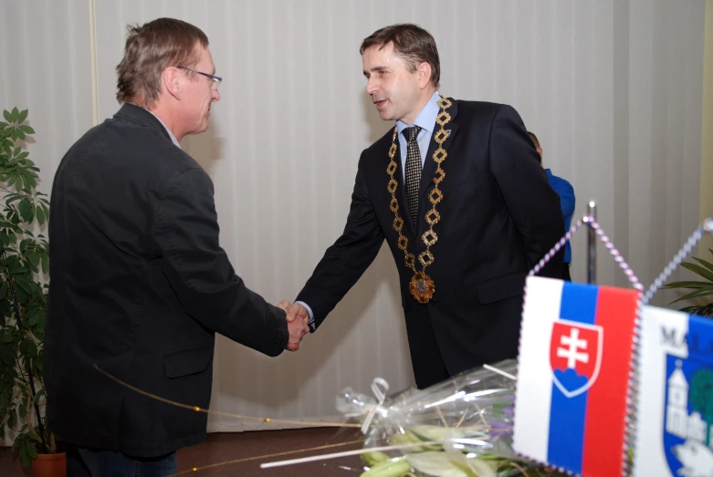 two men shaking hands near some decorative gifts