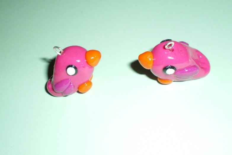 two pink objects with orange feet on white surface