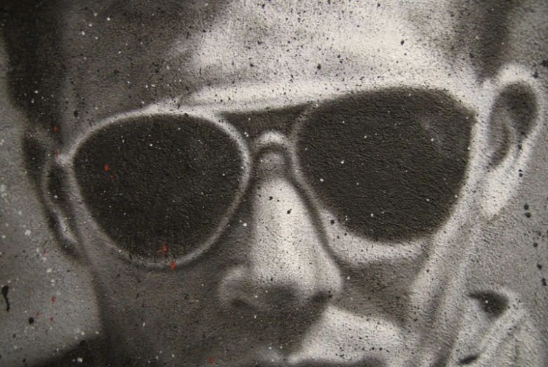 a man wearing sunglasses spray painted on a wall