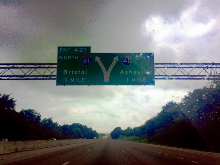 a green street sign hanging over a highway