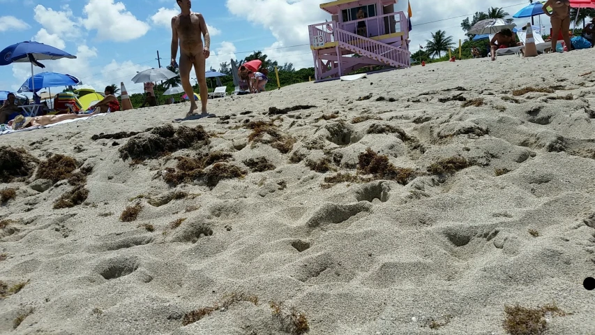 people are walking along the beach near some umbrellas