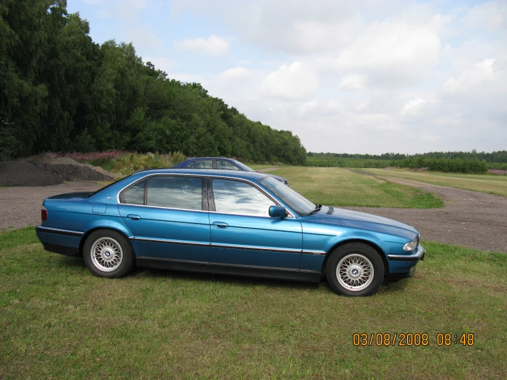 a blue car sits parked in the grass